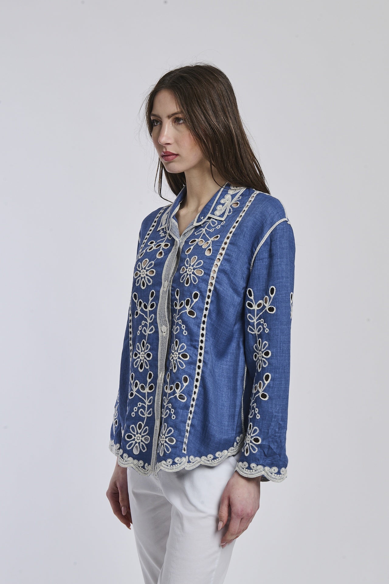 Donna con camicia a righe azzurre e bianche, maniche arrotolate e taglio leggermente oversize, per un aspetto rilassato.