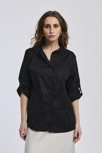 Camicia oversize nera, colletto alto, bottoni frontali e maniche arrotolate, perfetta per un outfit notturno.