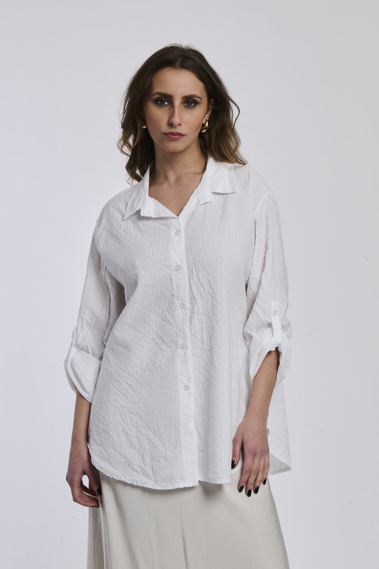 Camicia oversize bianca a righe, colletto a V sfiorato, bottoni frontali e maniche arrotolate, idea per outfit estivi.