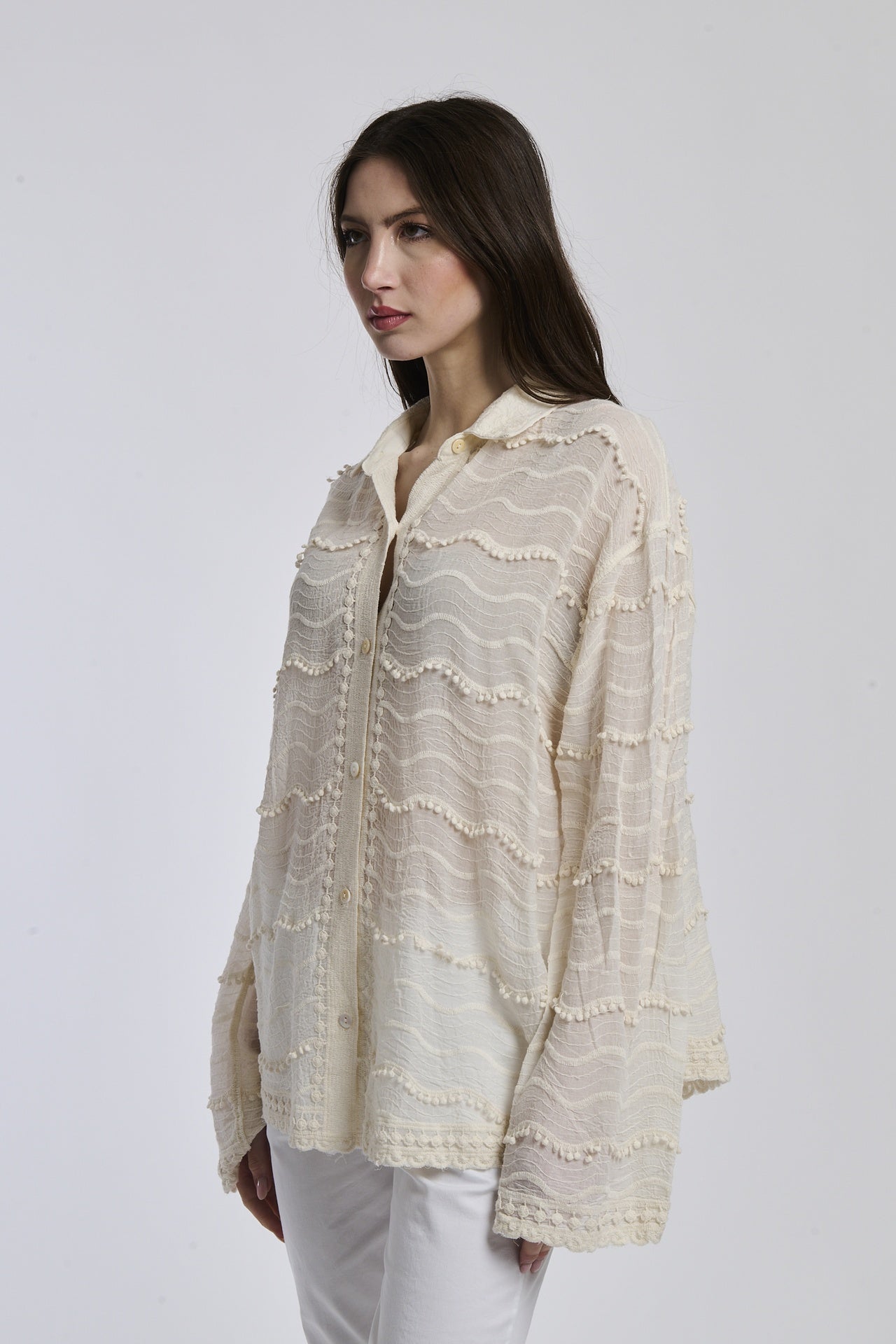 Outfit casual: camicia traslucida beige e pantaloni bianchi, donna con capelli lunghi e orecchini