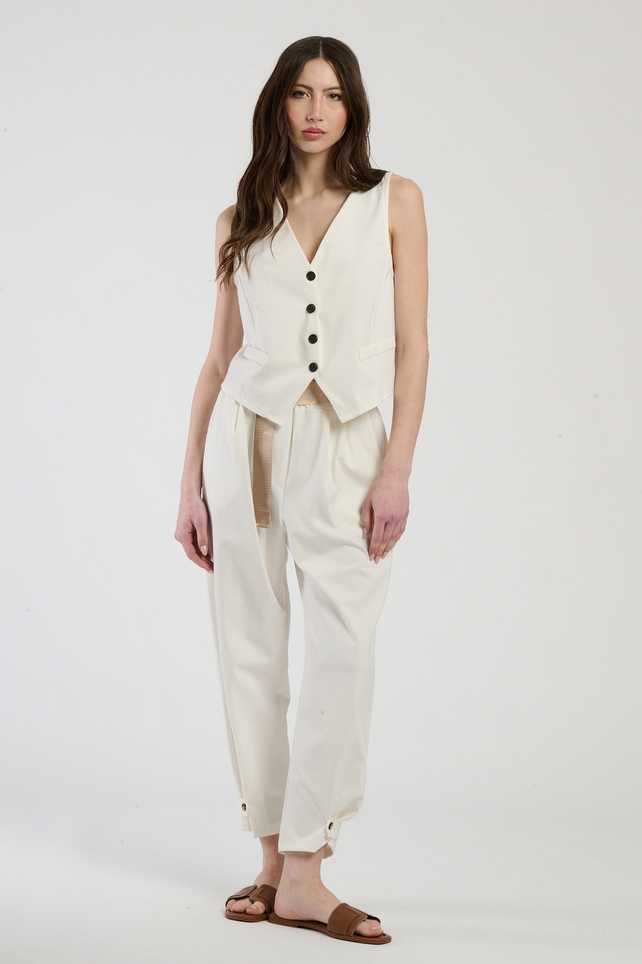 Modella in completo bianco: gilet senza spalline e pantaloni, eleganza pura e minimalista.