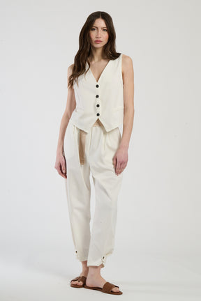 Modella in completo bianco: gilet senza spalline e pantaloni, eleganza pura e minimalista.