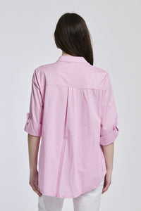 Camicia rosa oversize, colletto alto, maniche arrotolate, stile dolce e femminile.