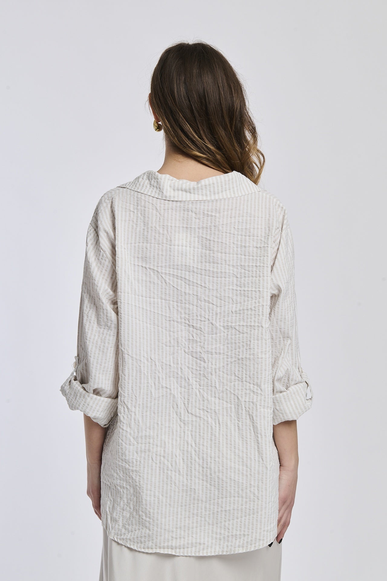 Camicia oversize a righe beige, colletto classico, bottoni e maniche arrotolate, stile minimalista.