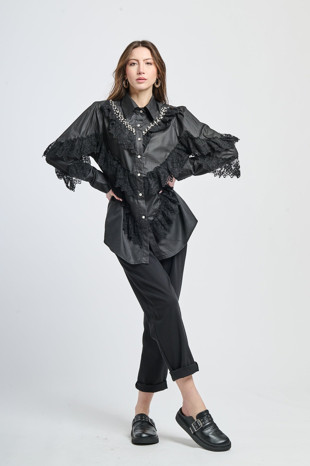 Camicia femminile in nero con dettagli di pizzo e chiodini, maniche a tromba irregolari.