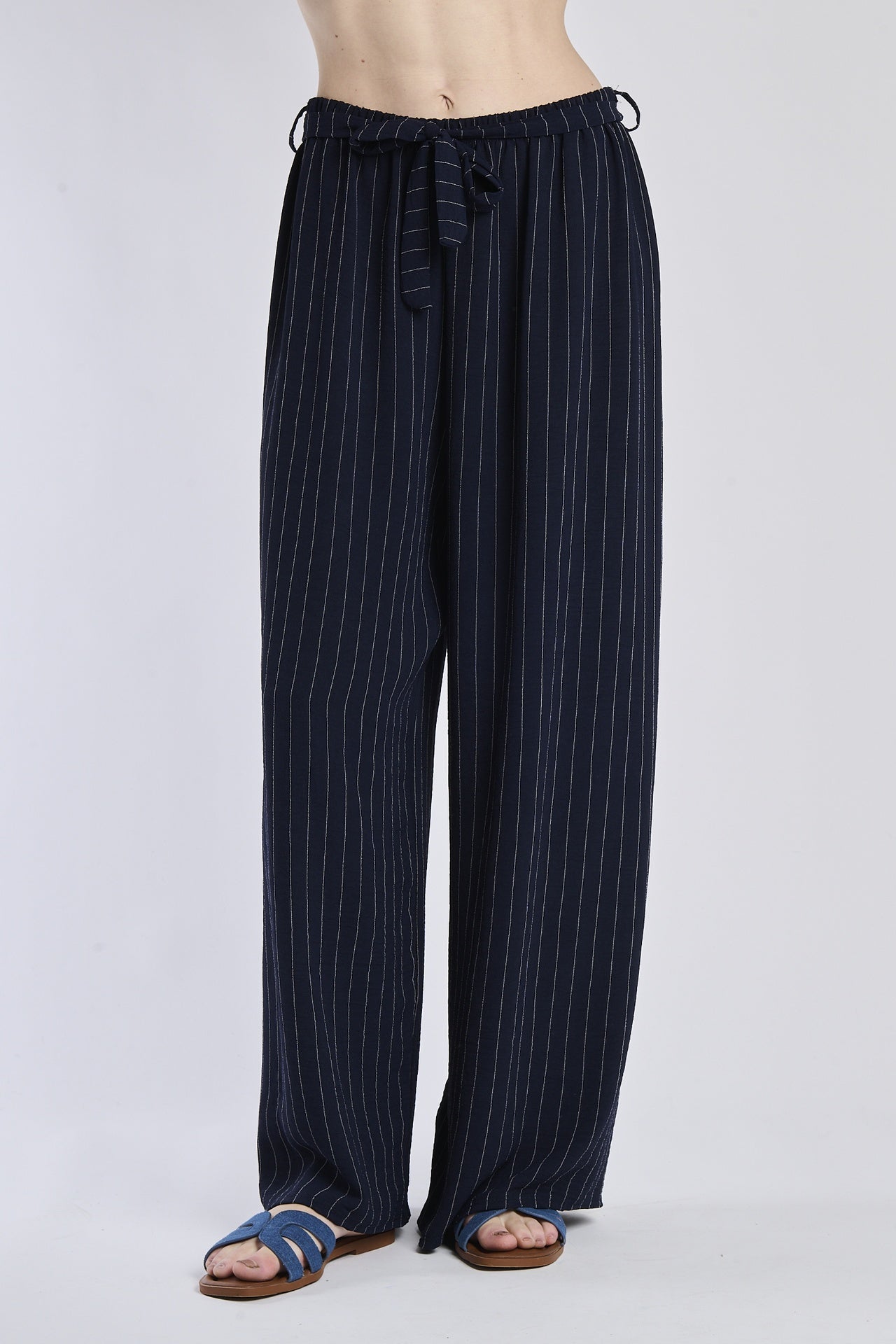 Pantaloni larghi navy con coulisse e nodo in vita, abbinati a sandali.