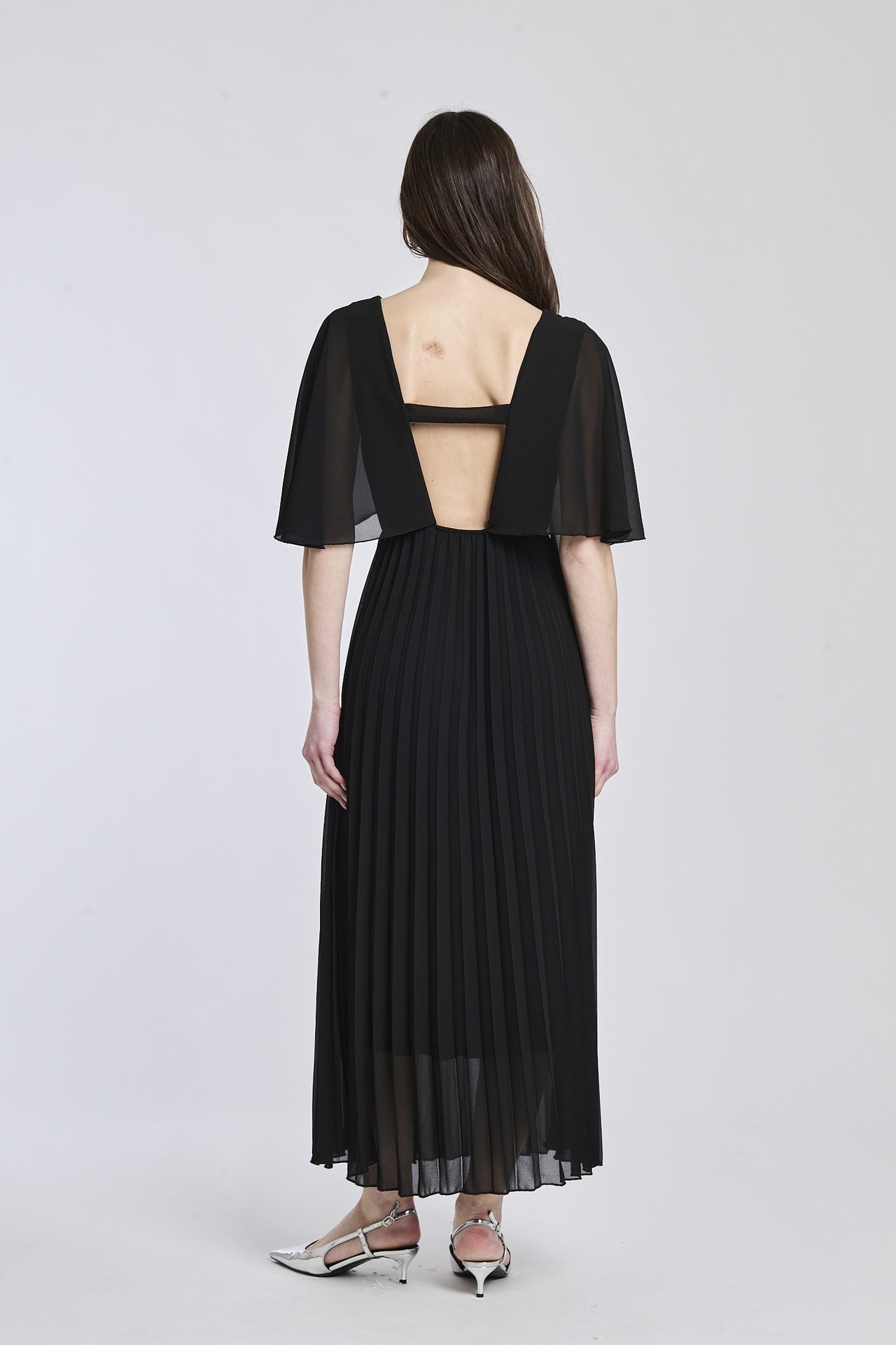 Vestito nero con falde al fondo, mantenendo lo stile elegante e classico, perfetto per occasioni formali.