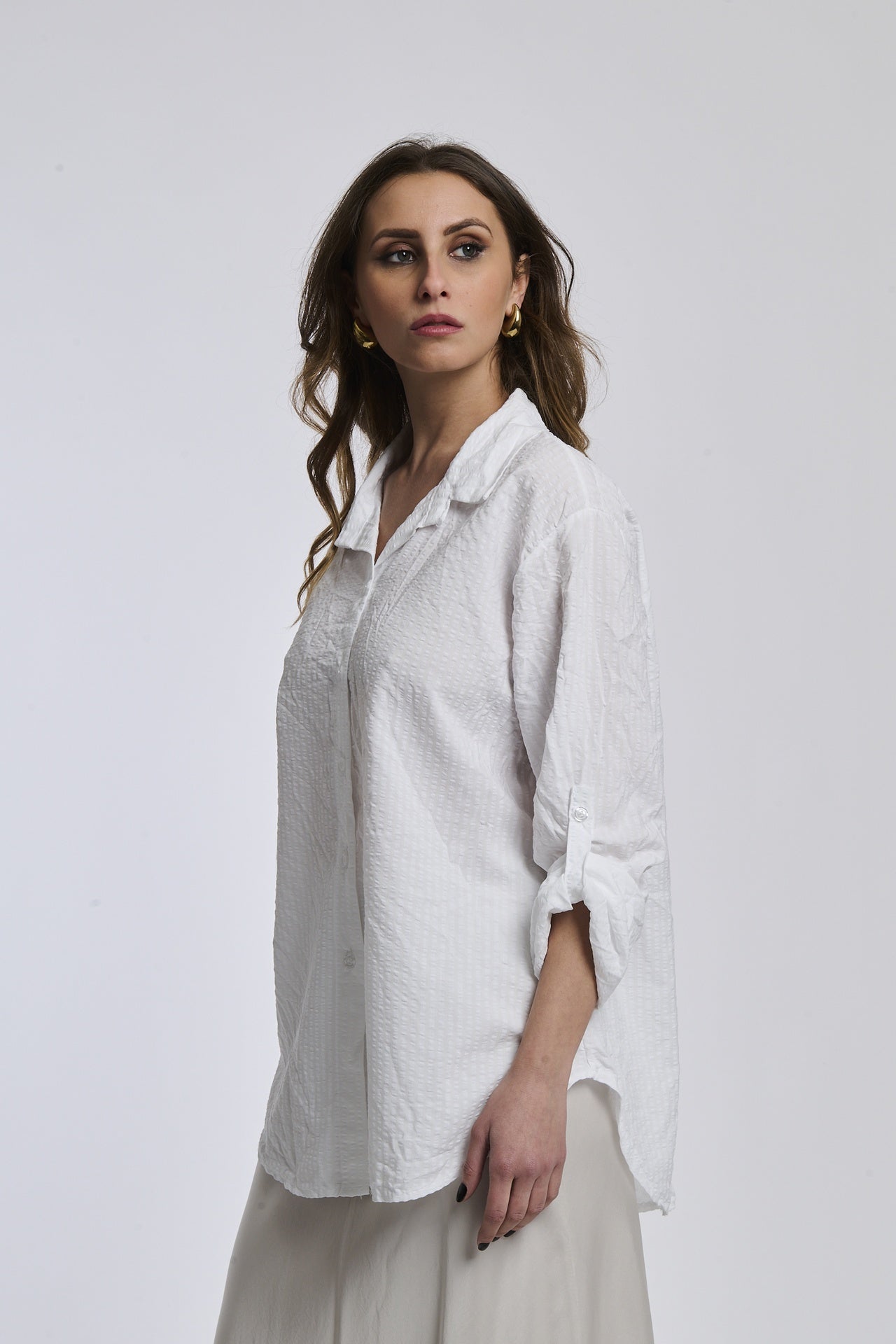 Camicia oversize a righe bianche, colletto classico, bottoni e maniche arrotolate, stile pulito e fresco.