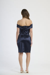 Modella in abito navy con plissé, stile preppy e sofisticato per serate formali.