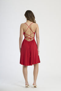 Vestito rosso in tessuto vibrante, silhouette a campana con bretelle sottili, ideale per eventi estivi e serate speciali.