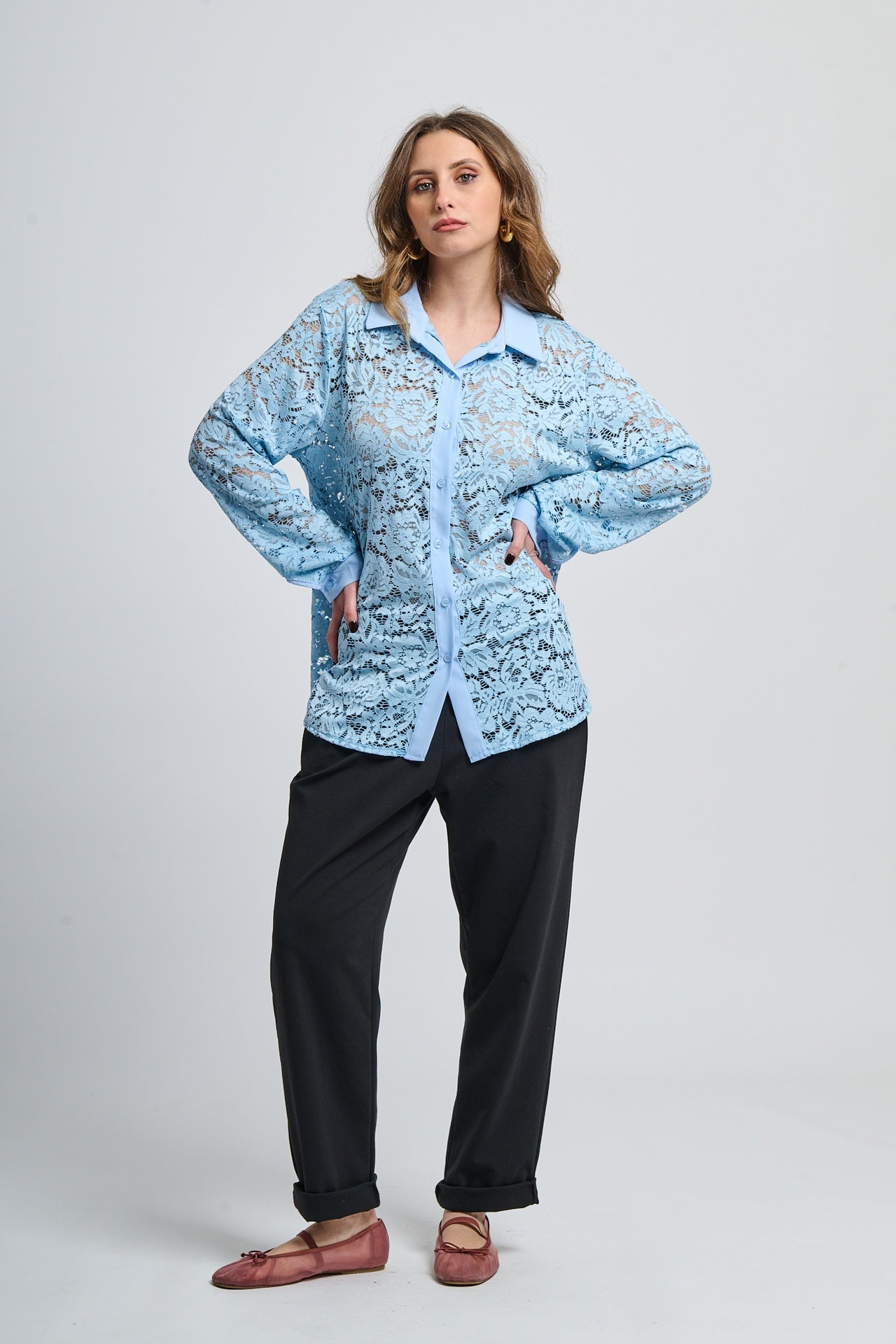 Camicetta azzurra con motivi, collo camiciera e maniche lunghe, abbinata a pantaloni neri.