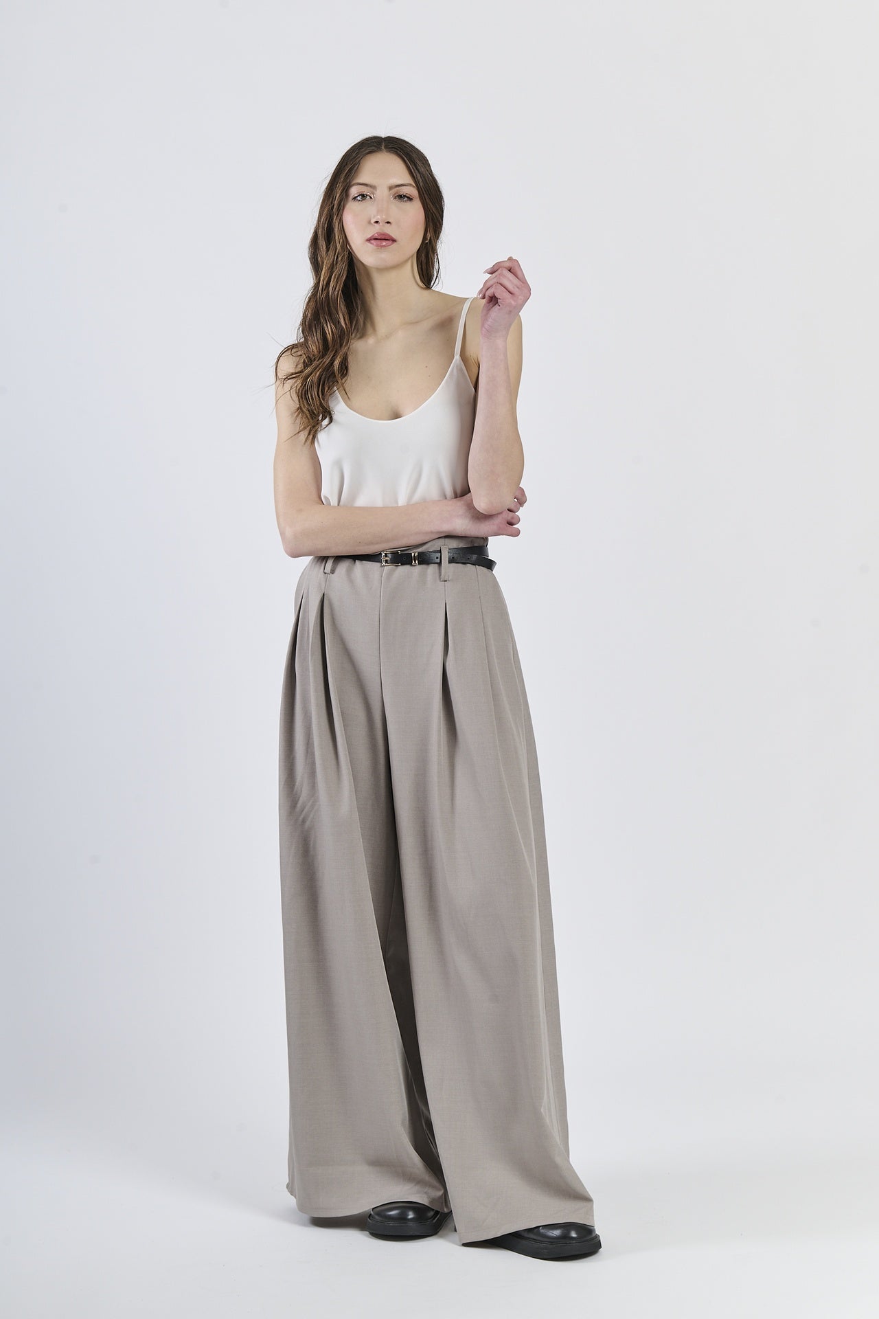 Outfit con top bianco e pantaloni color fango, cinghia nera decorativa