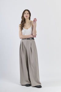 Outfit con top bianco e pantaloni color fango, cinghia nera decorativa