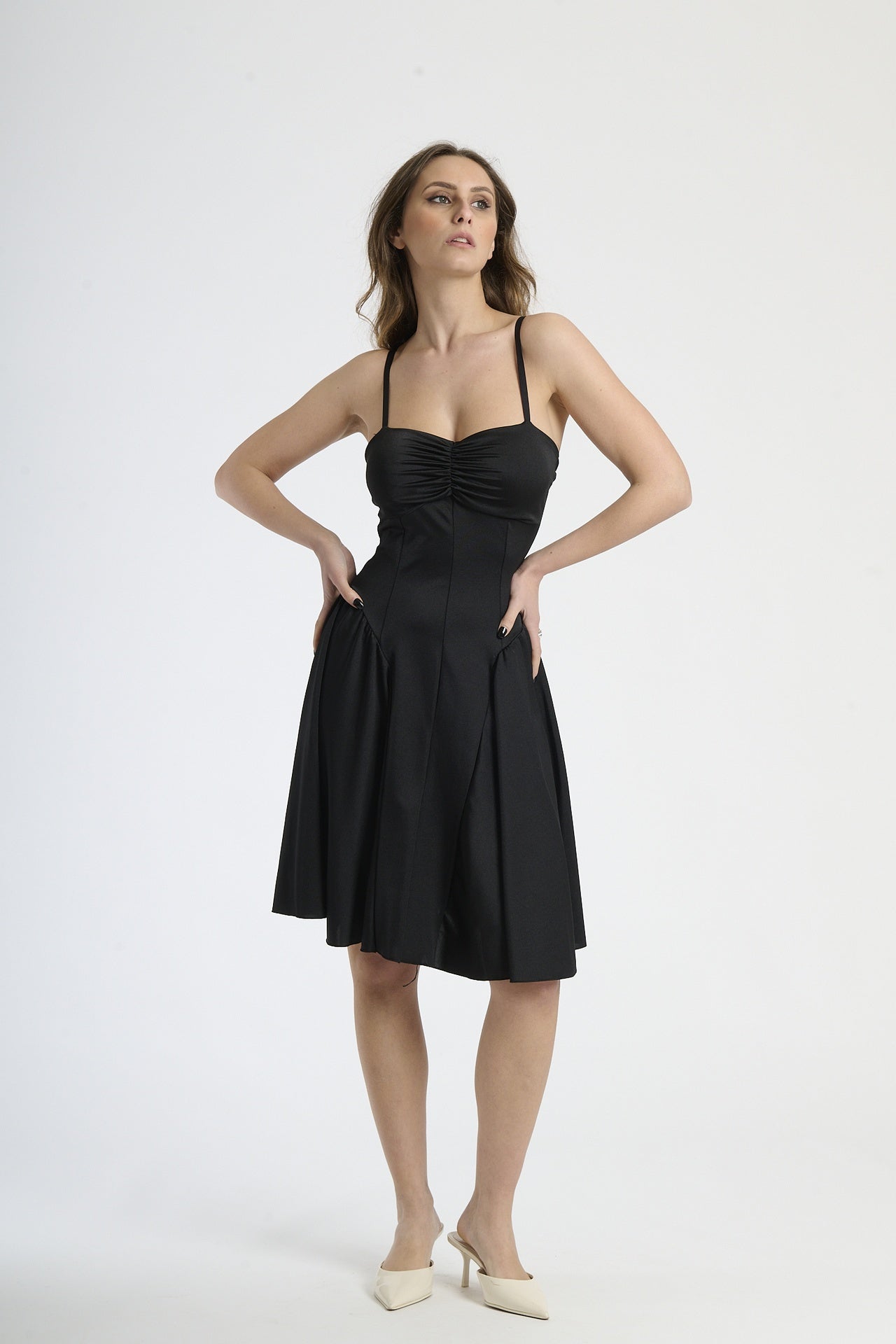 Donna con abito nero a spalline, eleganza senza tempo e sensualità.