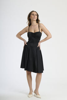 Donna con abito nero a spalline, eleganza senza tempo e sensualità.