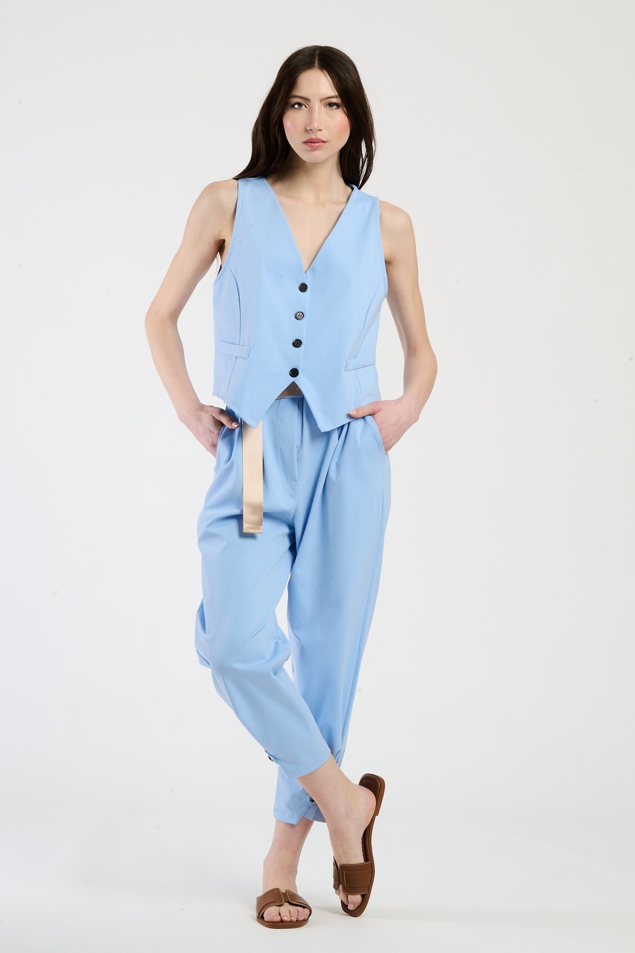 Donna elegante con completo azzurro: gilet senza spalline e pantaloni, stile raffinato e moderno.