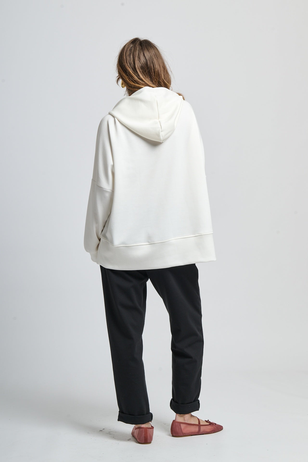 Outfit con felpa bianca con cappuccio e pantaloni neri, scarpe mocassini