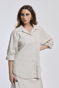 Camicia oversize beige, stile minimalista, bottoni frontali, maniche arrotolate.