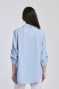 Camicia oversize azzurra, stile casual, bottoni frontali, maniche arrotolate.