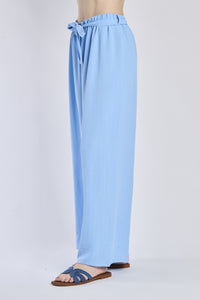 Pantaloni fluido azzurri, taglio ampio, nodo decorativo in vita, perfetti per l’estate.