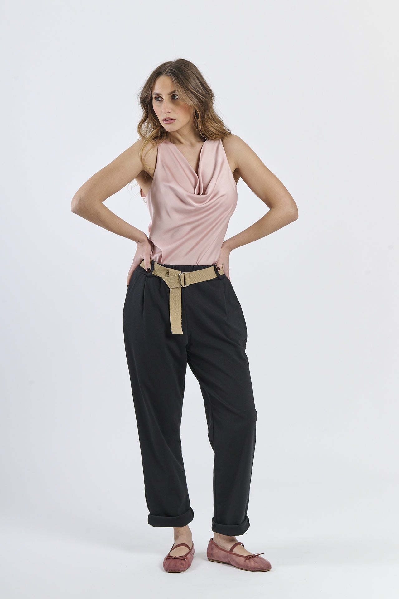 Look con top senza maniche rosa e pantaloni neri ampi, contrasto di texture
