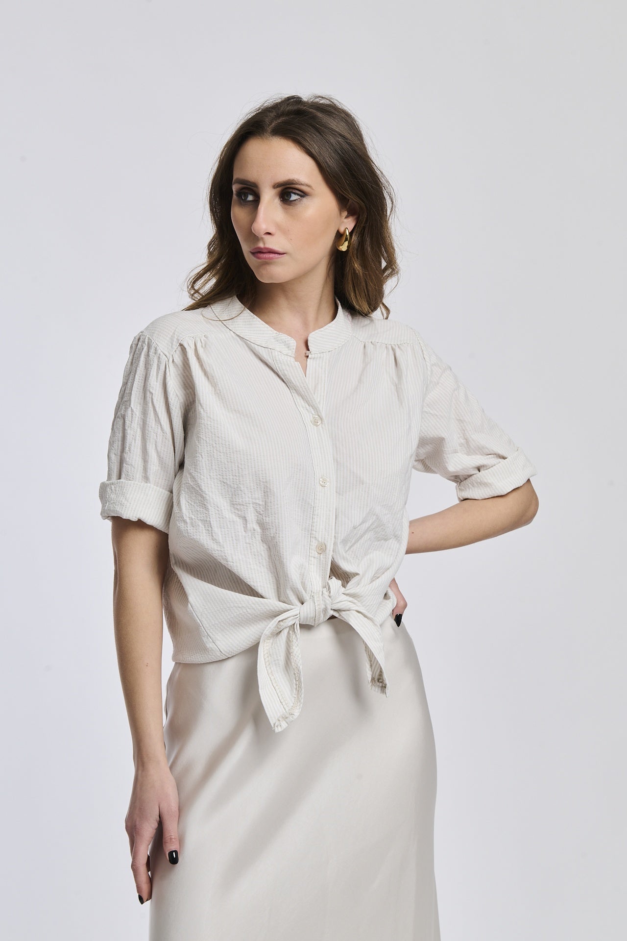 Camicia a righe beige e bianche da donna, nodo sul petto, che aggiunge un tocco di romanticismo.
