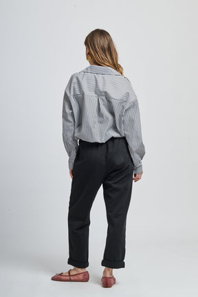 Combinazione camicia nero a righe e pantaloni bianchi elegante