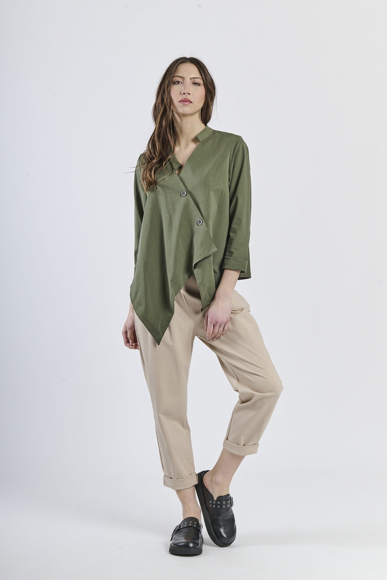 Outfit con camicia verde asimmetrica e pantaloni beige chiari, scarpe mocassini scure