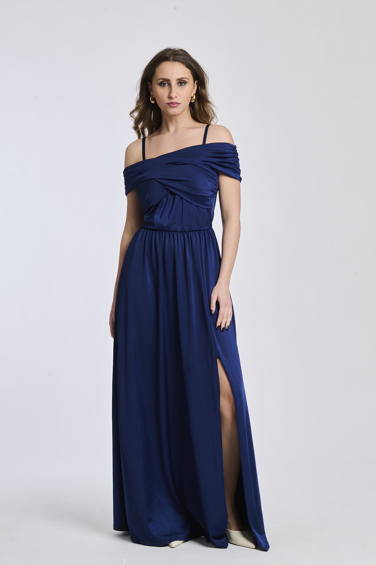 Donna con abito lungo navy, spalline scollate, fascia in vita e apertura laterale classica.