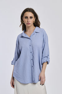 Camicia navy a righe, collo camiciera, maniche a 3/4, abbinata a pantaloni chiari.