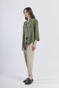 Look con camicia verde a taglio asimmetrico, pantaloni beige a gamba larga e mocassini marroni