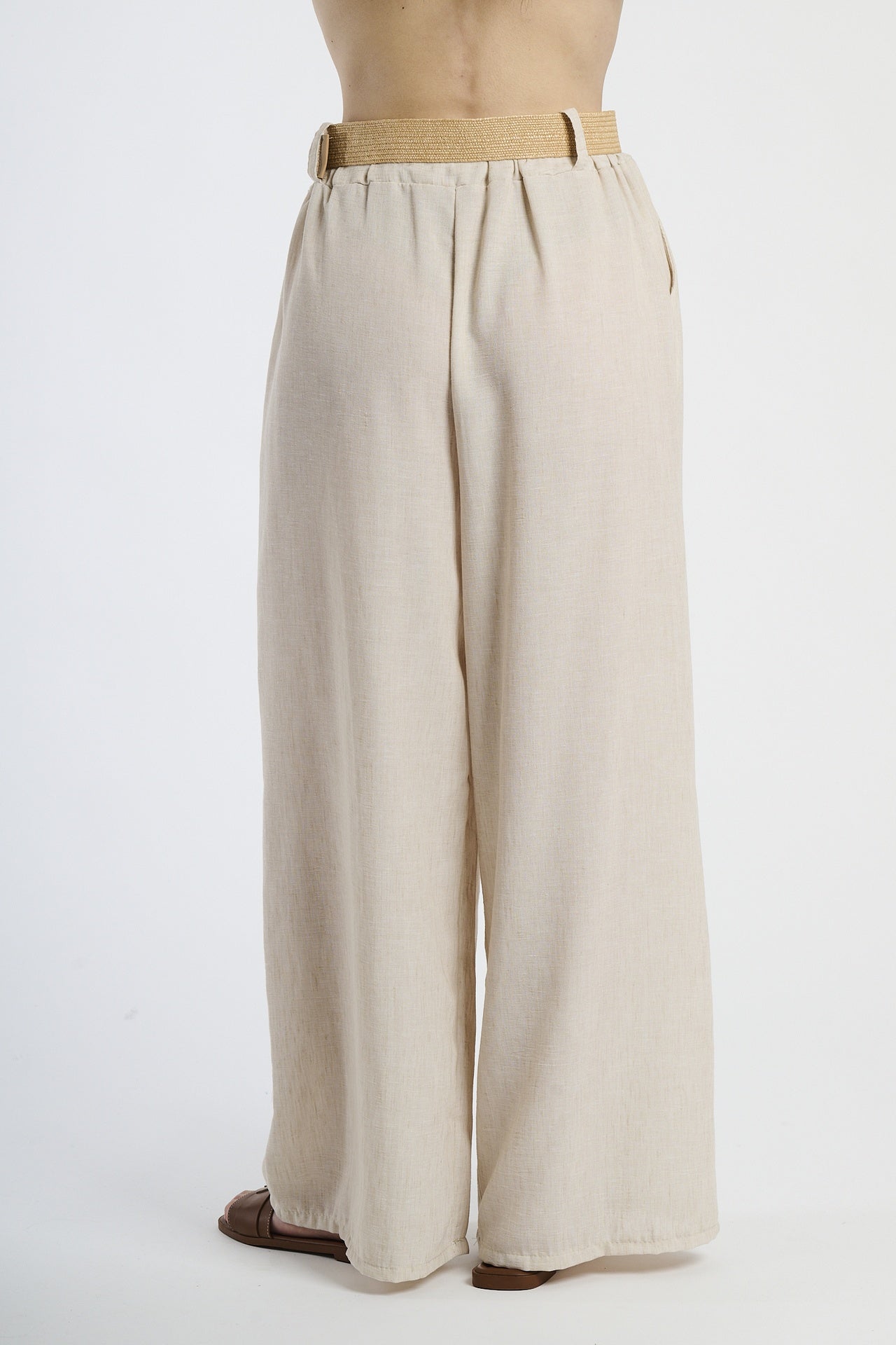 Modella indossa pantaloni beige larghi, look casual e raffinato.