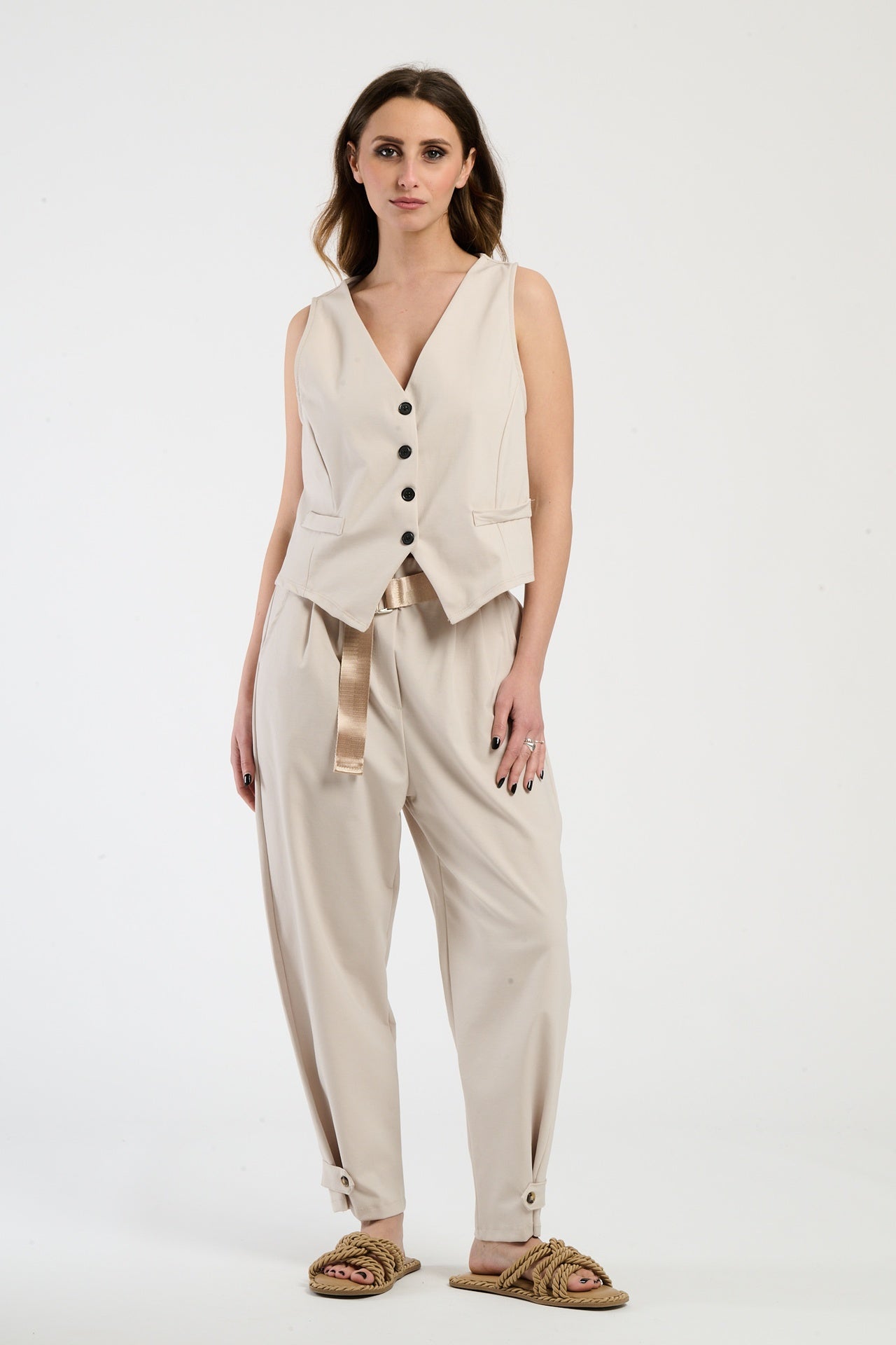 Donna con completo beige: gilet e pantaloni, armonia di tonalità neutre e eleganza.