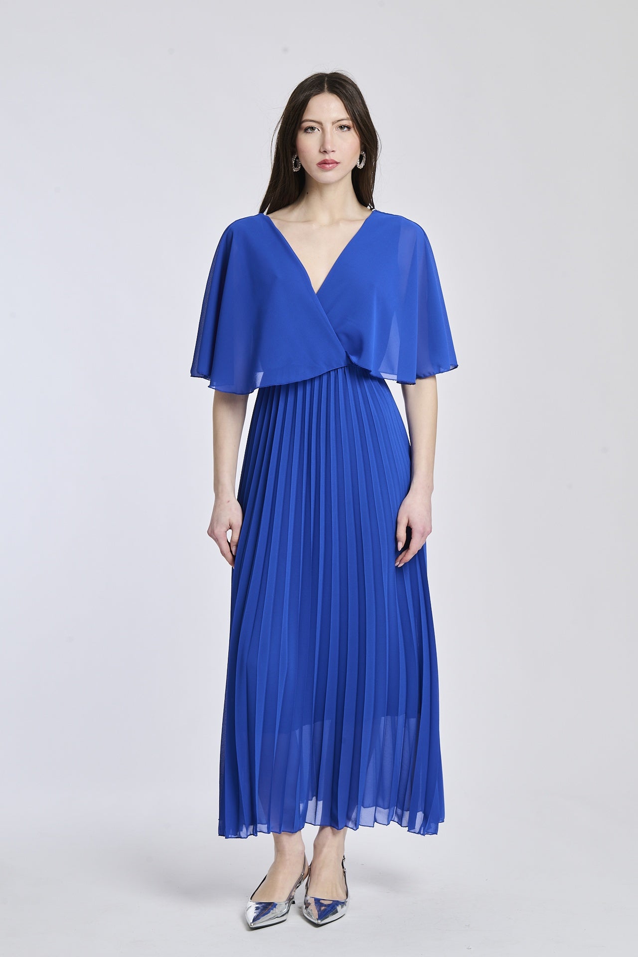 Un abito in bluette con lo stesso design crociato e maniche a mantello, creando un'atmosfera di serenità e vitalità.