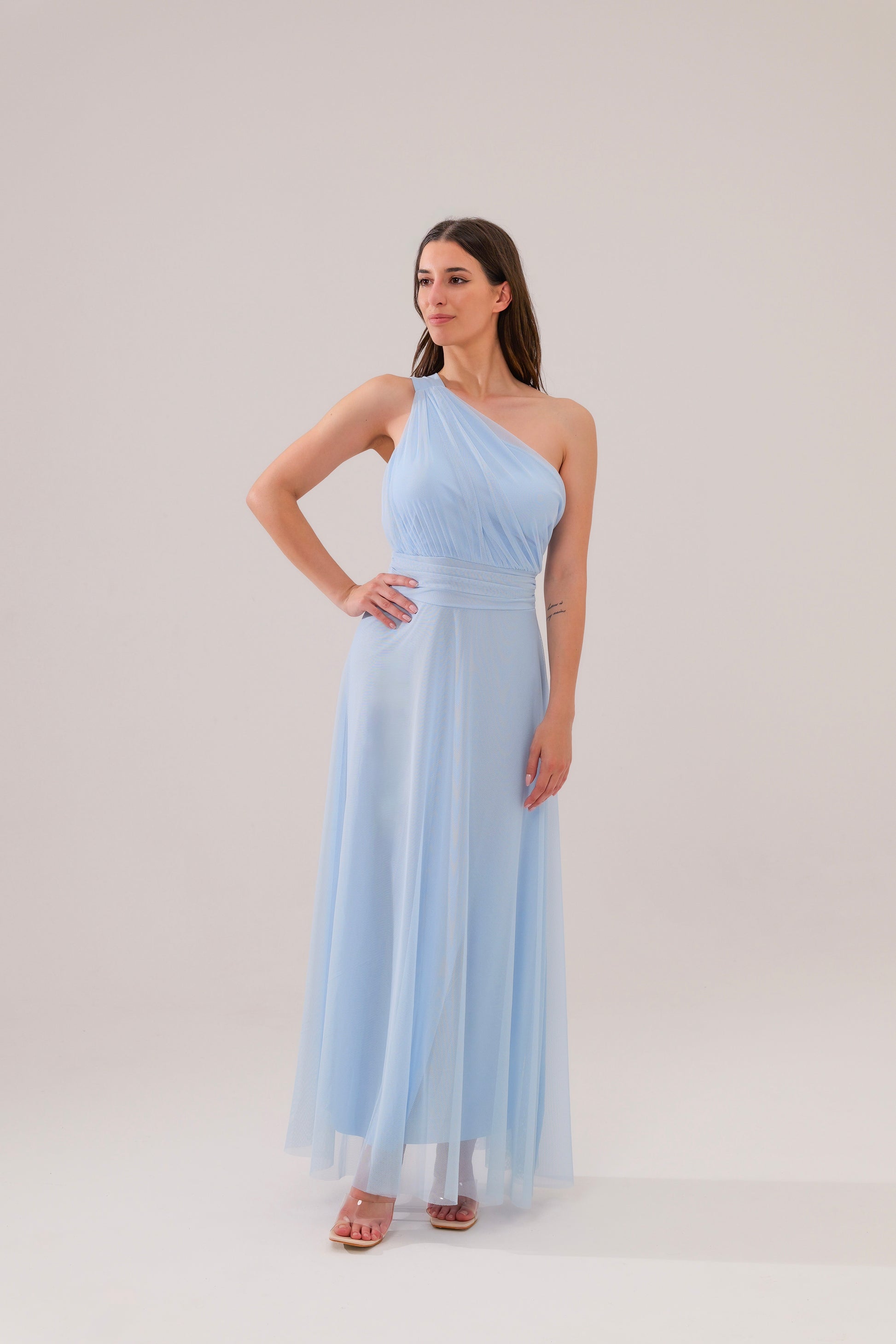 Questo abito celeste a spalla unica, in tulle leggero, è la definizione di eleganza eterea. Il taglio aderente al busto e la gonna fluida regalano un look da favola, perfetto per cerimonie o eventi esclusivi. 
