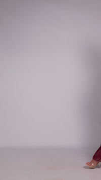 Donna con abito colore vino elegante, collo alto a imbarcatura, gonna lunga, foulard in tulle trasparente, look elegante e vissuto.